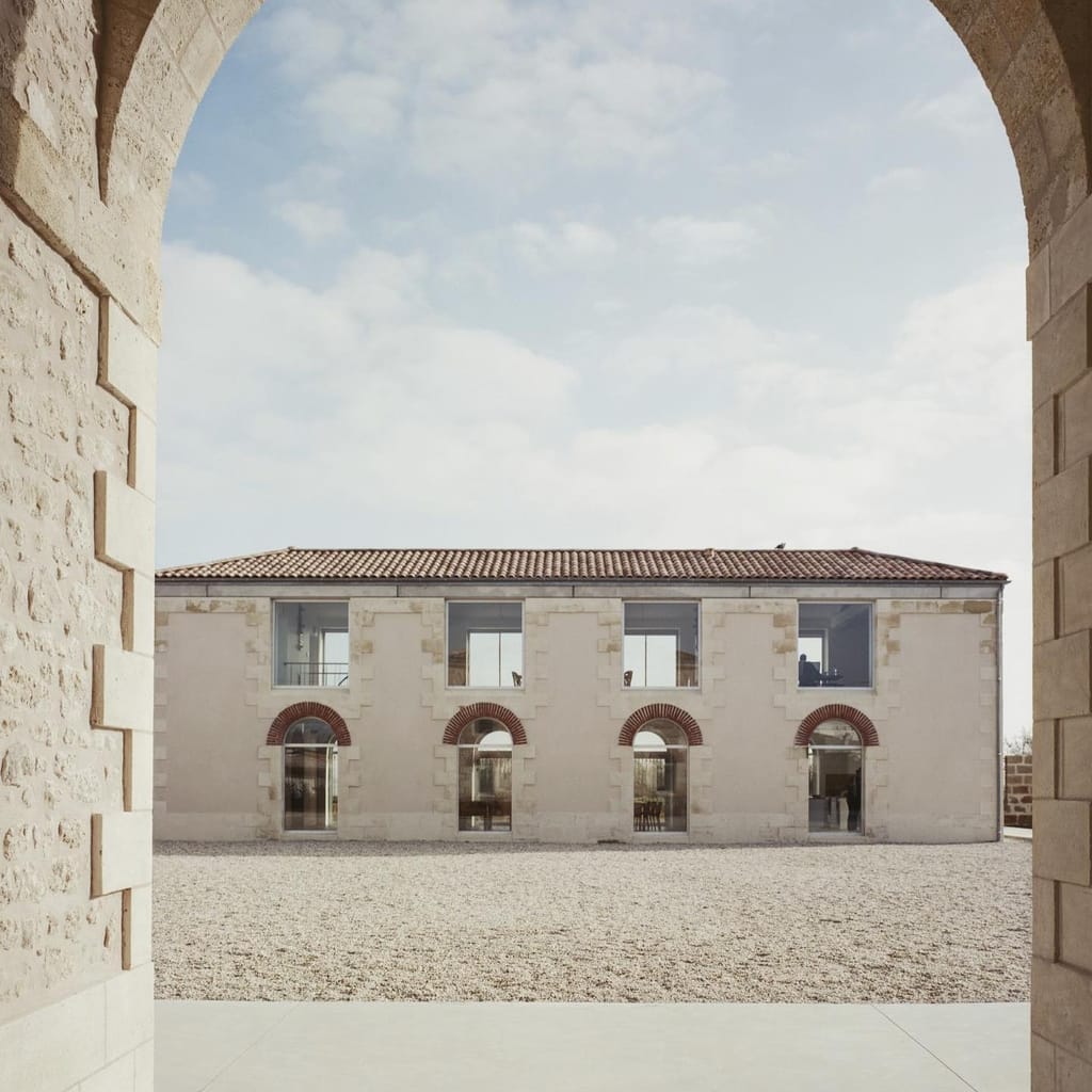 Cour intérieure patrimoniale vue à travers une arcade en pierre.