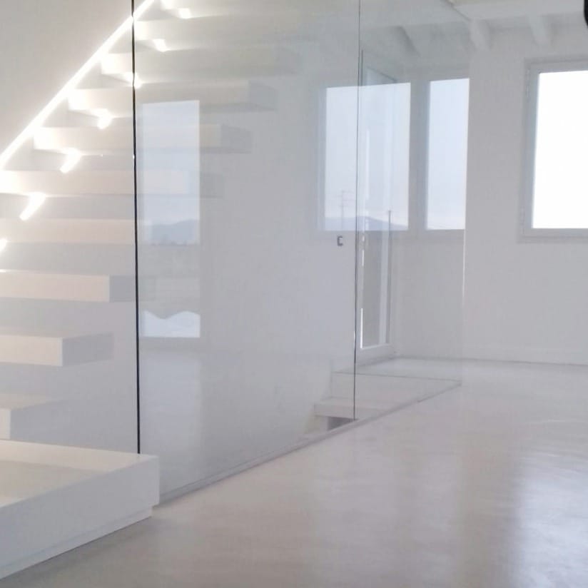 Volume traversant, escalier blanc suspendu sur sol microciment clair.