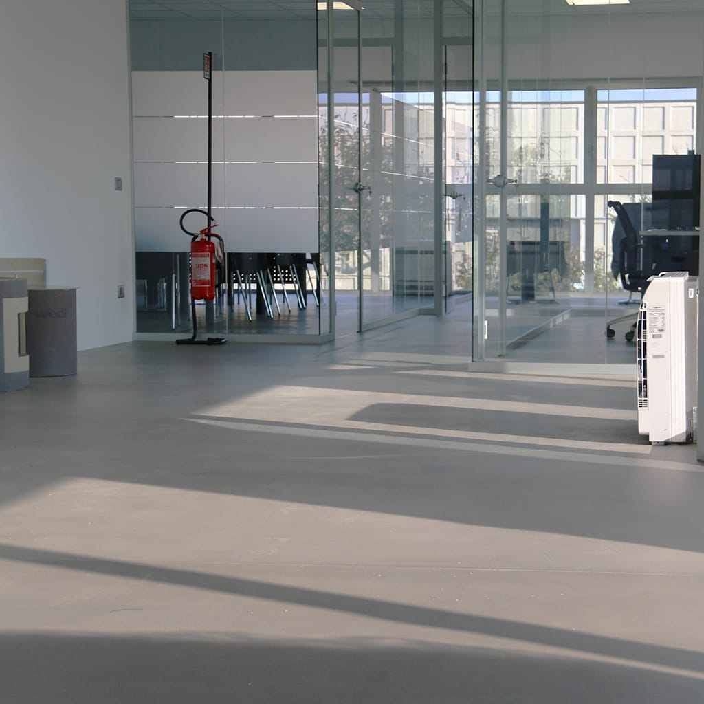 Hall d'accueil d'entreprise, sol microciment gris.
